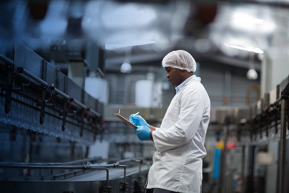 Homme dans une entreprise de production agroalimentaire en train de prendre des notes