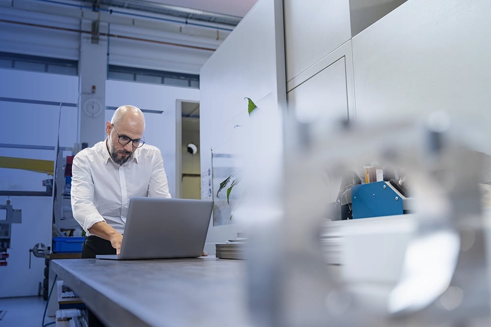 Man on laptop in manufacturing factory