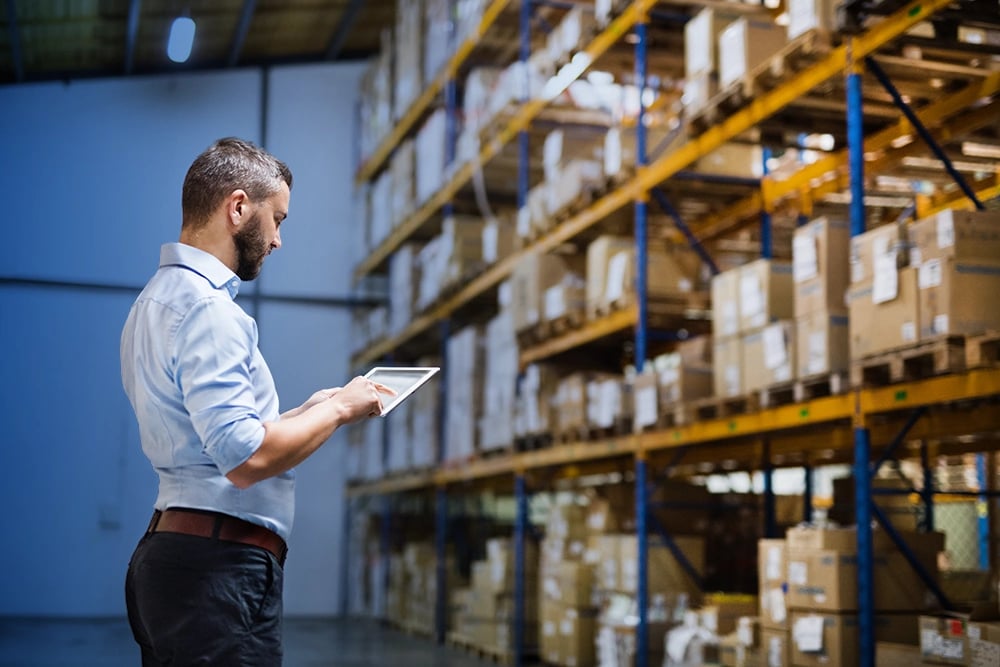 Homme qui recherche des produits dans un entrepôt depuis sa tablette